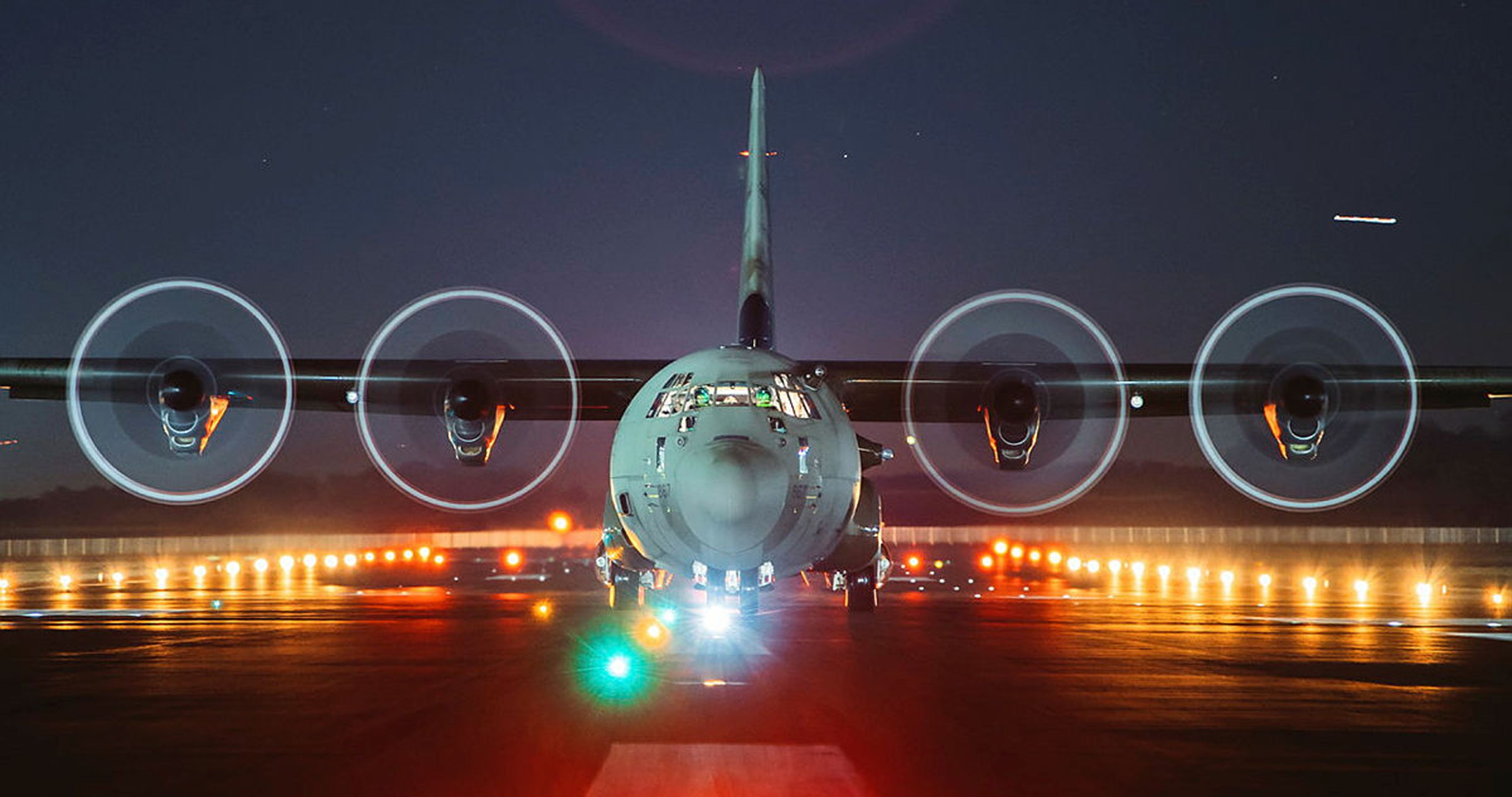 Image showing military personnel jumping out of a plane. The camera is behind the person who is jumping so the ground is visible below