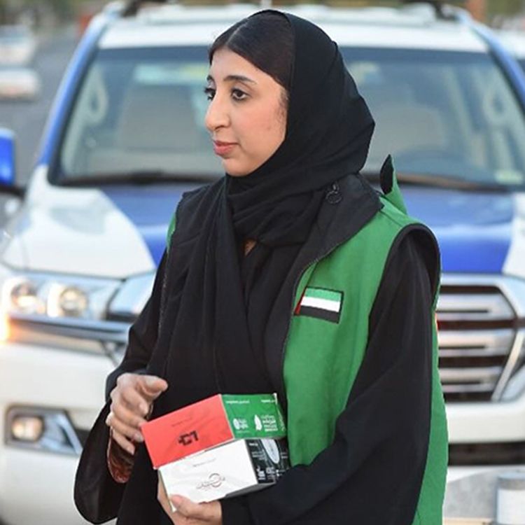 A woman standing at the roadside holding food boxes