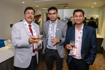 Three men in suits, holding up drinks and smiling into the camera